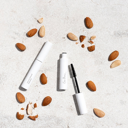 toma aerea del envase de la mascara de almendras sobre fondo blanco y alendras al rededor disponible en blumma