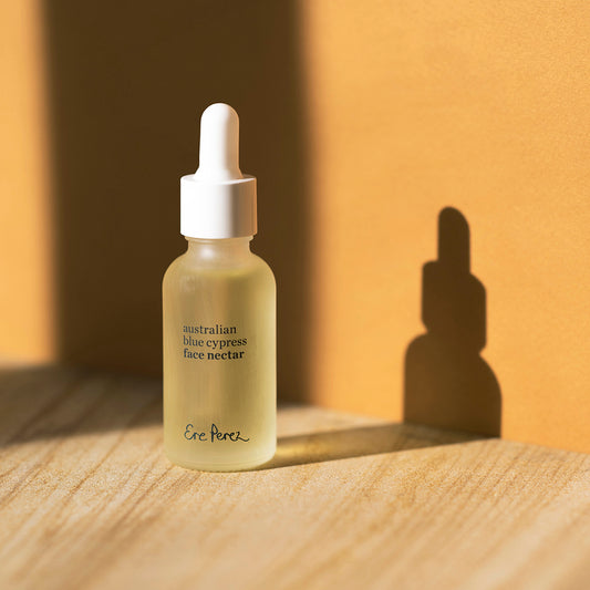 frasco de vidrio de Nectar facial de cipres azul de Ere Perez con fondo de colores disponible en BLUMMA