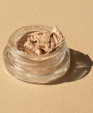 envase de vidrio sostenible abierto mostrando la textura del producto base corrector de arnica en tono latte ere perez disponible en blumma