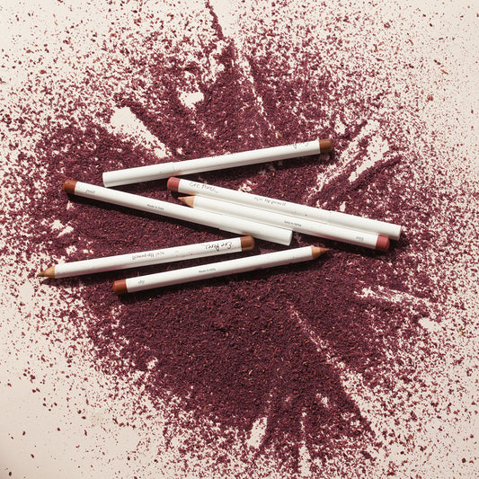 seis delineadores de labios ere perez sobre polvo color violeta y fondo blanco