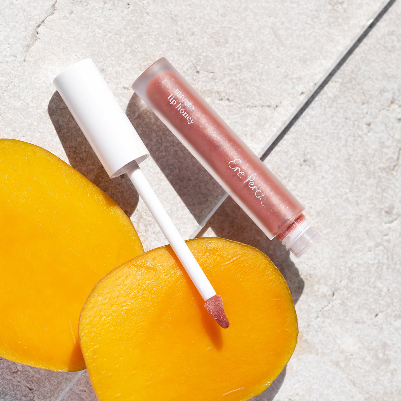 vista aerea envase sostenible de lipgloss con mango ere perez tono chilli con mangos a su alrededor humectante
