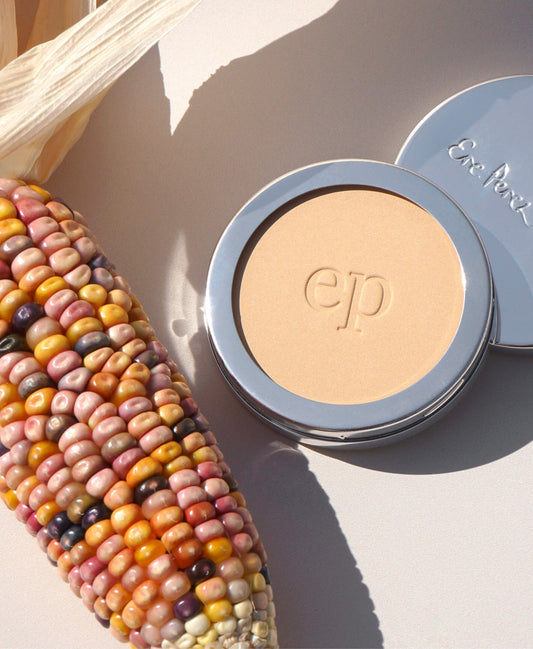 Polvo traslucido de maiz Ere Perez con su ingrediente principal, el maiz a un costado. disponible en BLUMMA