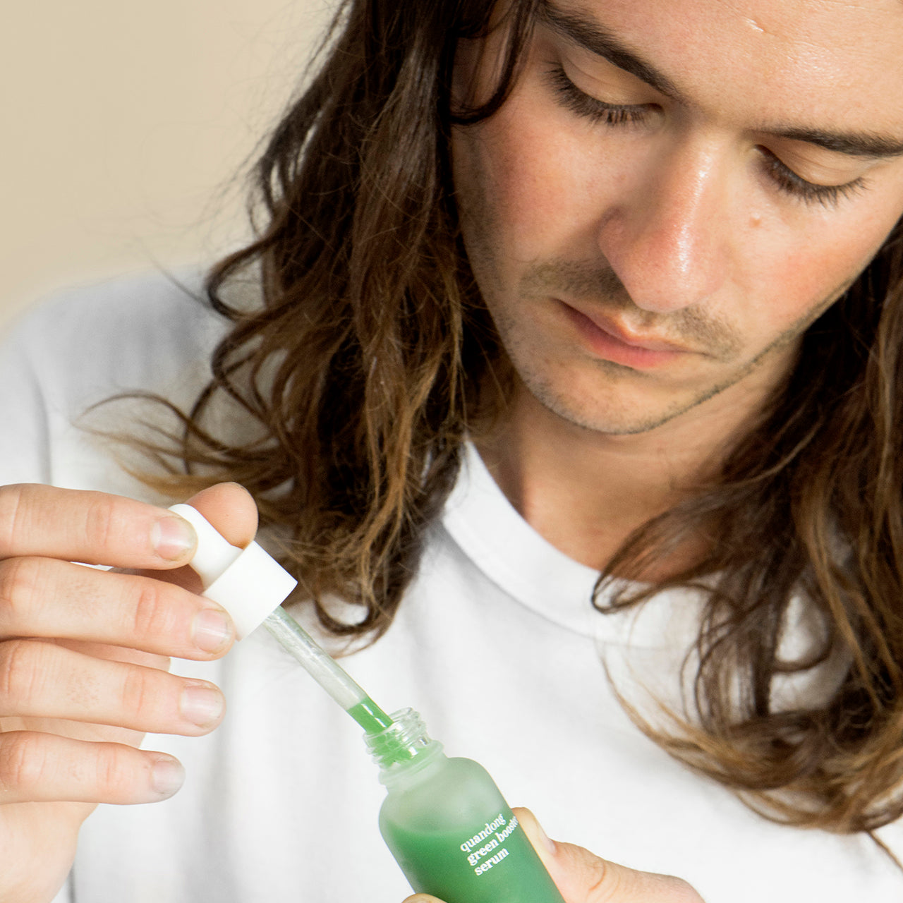 retrato de modelo masculino sosteniendo el envase de vidrio del suero verde hidratante ere perez disponible en blumma