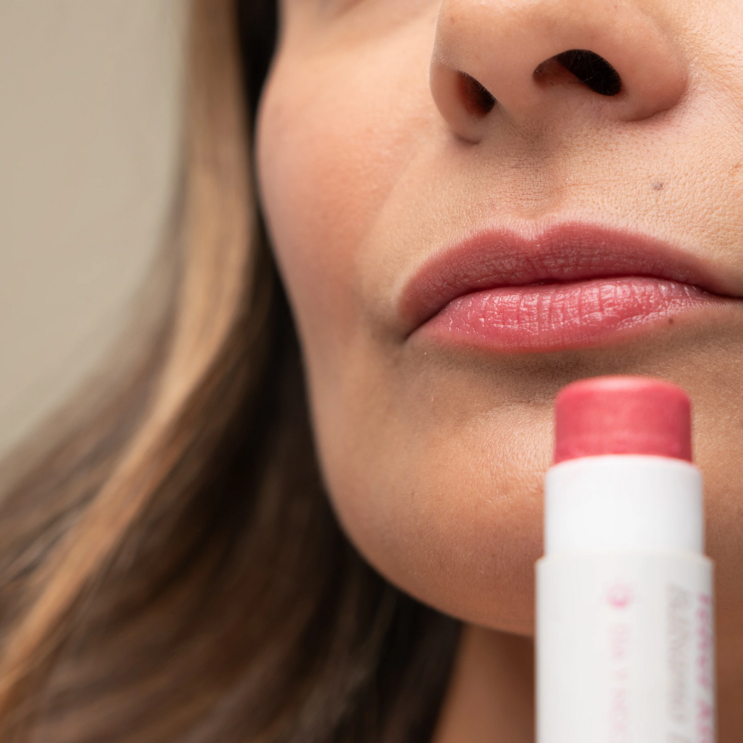 retrato de modelo femenina con acercamiento a sus labios con el balsamo hidratante con color aplicado de avoroots