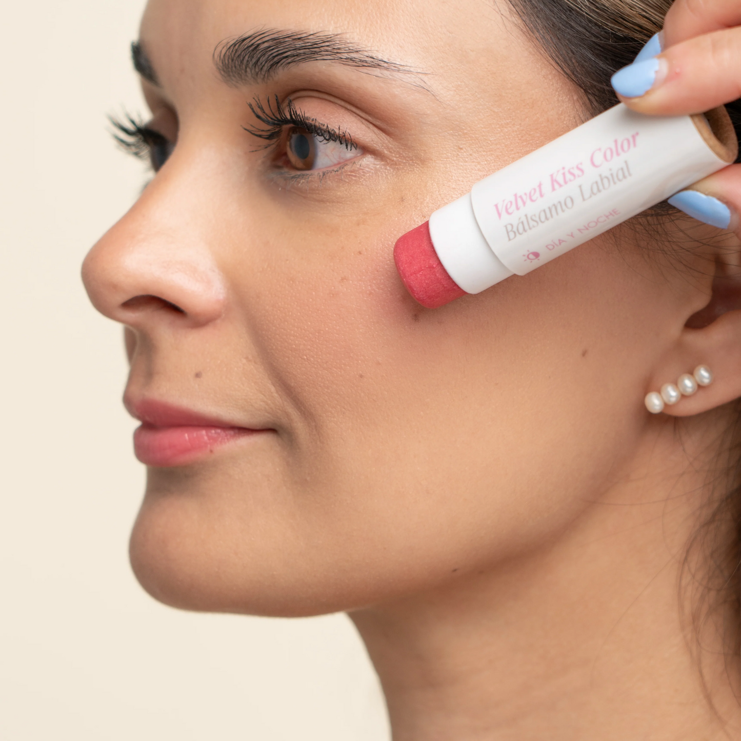 retrato de modelo femenina apliacando el balsamo labial hidratante con color en las mejillas avoroots