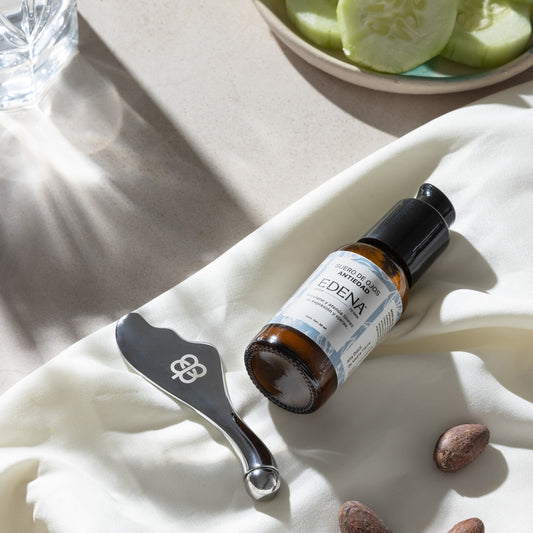 vista aerea del suero de ojos antiedad y roller para masajes sobre tela blanca con granos de cafe y rodajas de pepino