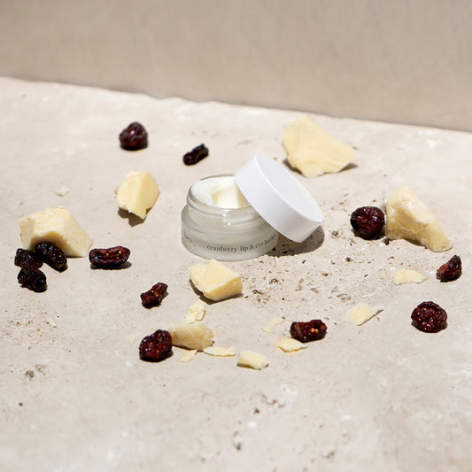 Crema con arandano para ojos y labios Ere Perez sobre base de marmol con frutos y manteca de karite disponible en BLUMMA