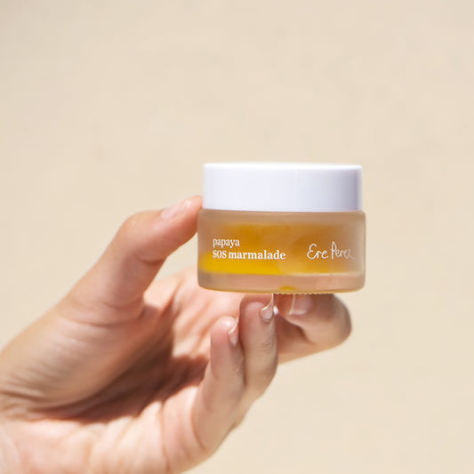 Jalea sos de papaya Ere Perez con fondo beige vista de frente detenida con mano en BLUMMA