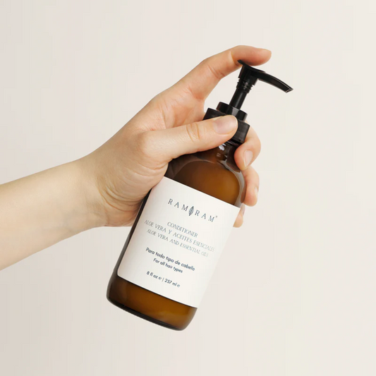 vista frontal de envase de vidrio color ambar del acondicionador de aloe vera con aceites esenciales de ram ram en fondo blanco