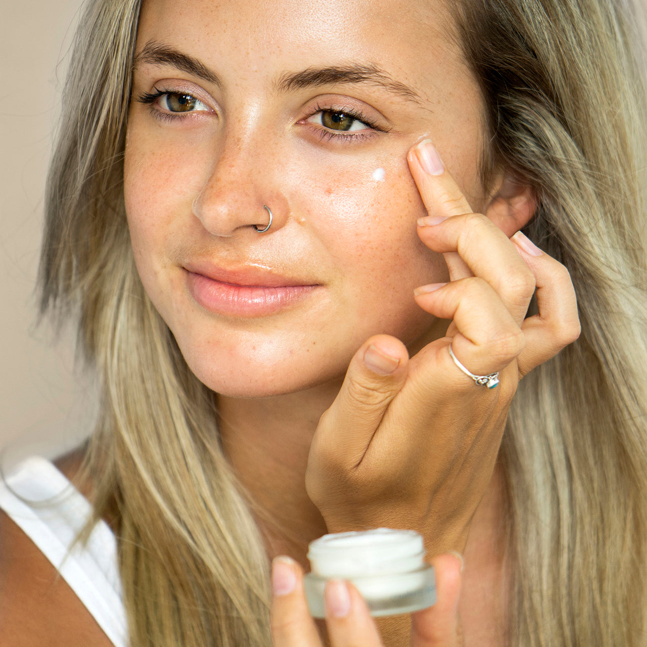 Mujer blanca colocando alrededor de los ojos la crema con arandano para ojos y labios Ere Perez disponible en BLUMMA