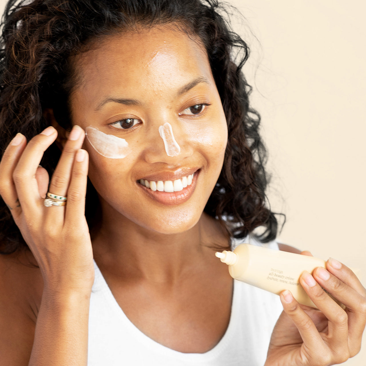 Mujer sonriente aplicando crema facial con Moringa Ere Perez en mejillas disponible en BLUMMA