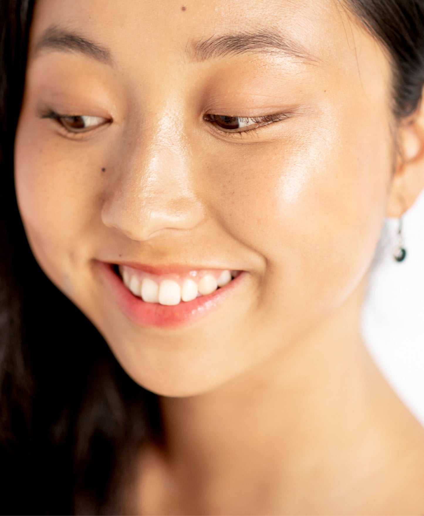 retrato de mujer sonriendo con la piel maquillada con base corrector de arnica en tono caramel ere perez disponible en blumma