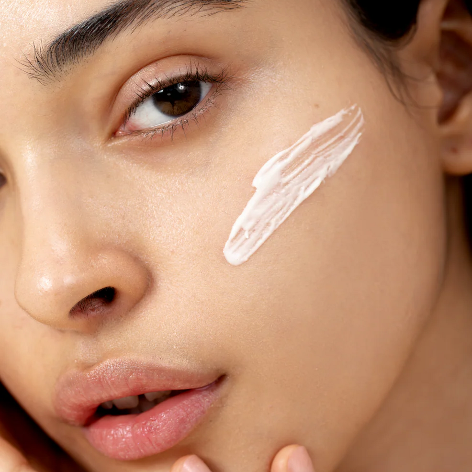 retrato de modelo con una pequeña cantidad de crema facial aplicada en la mejilla 