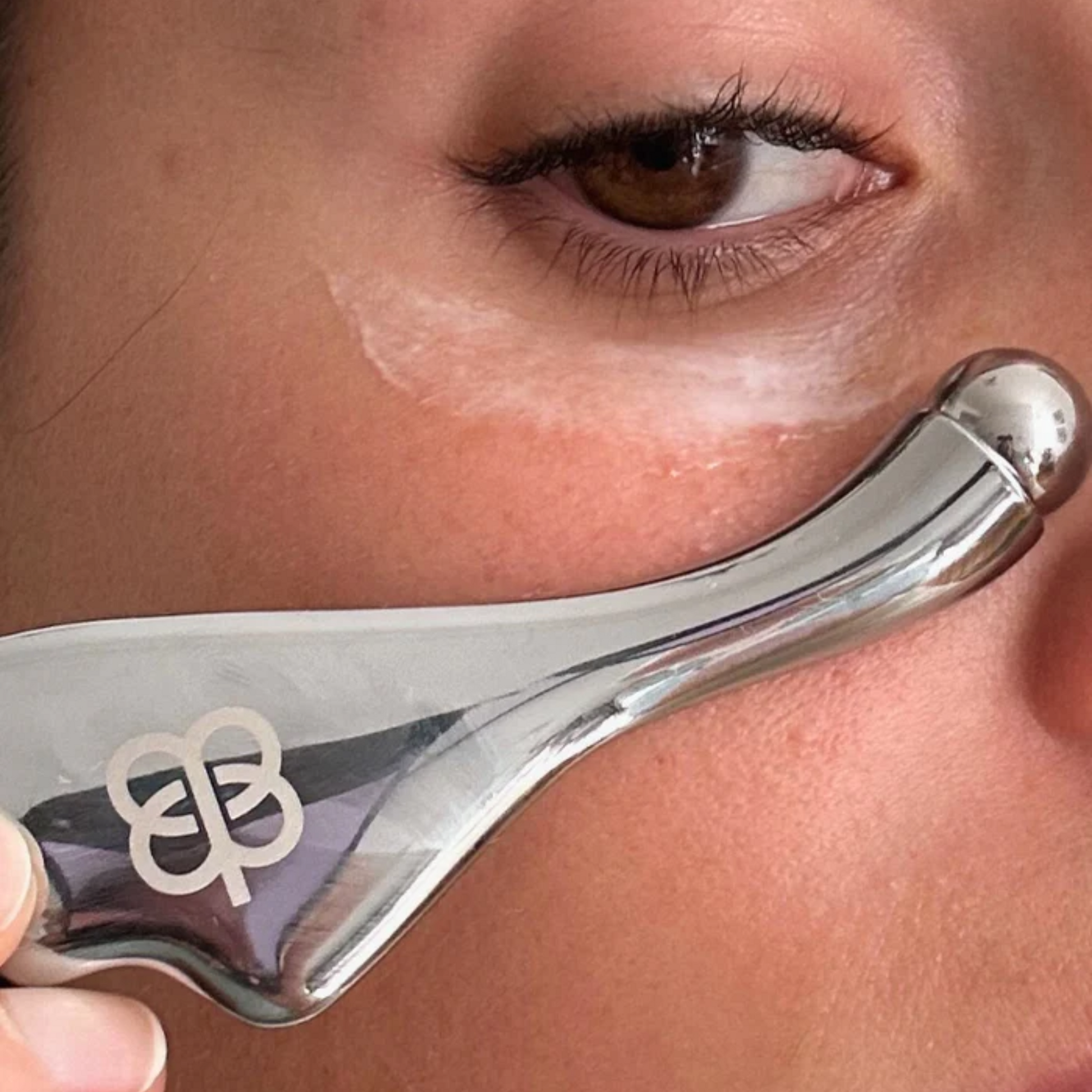 retrato de modelo usando el roller para masajes para aplicar el suero de ojos antiedad de edena