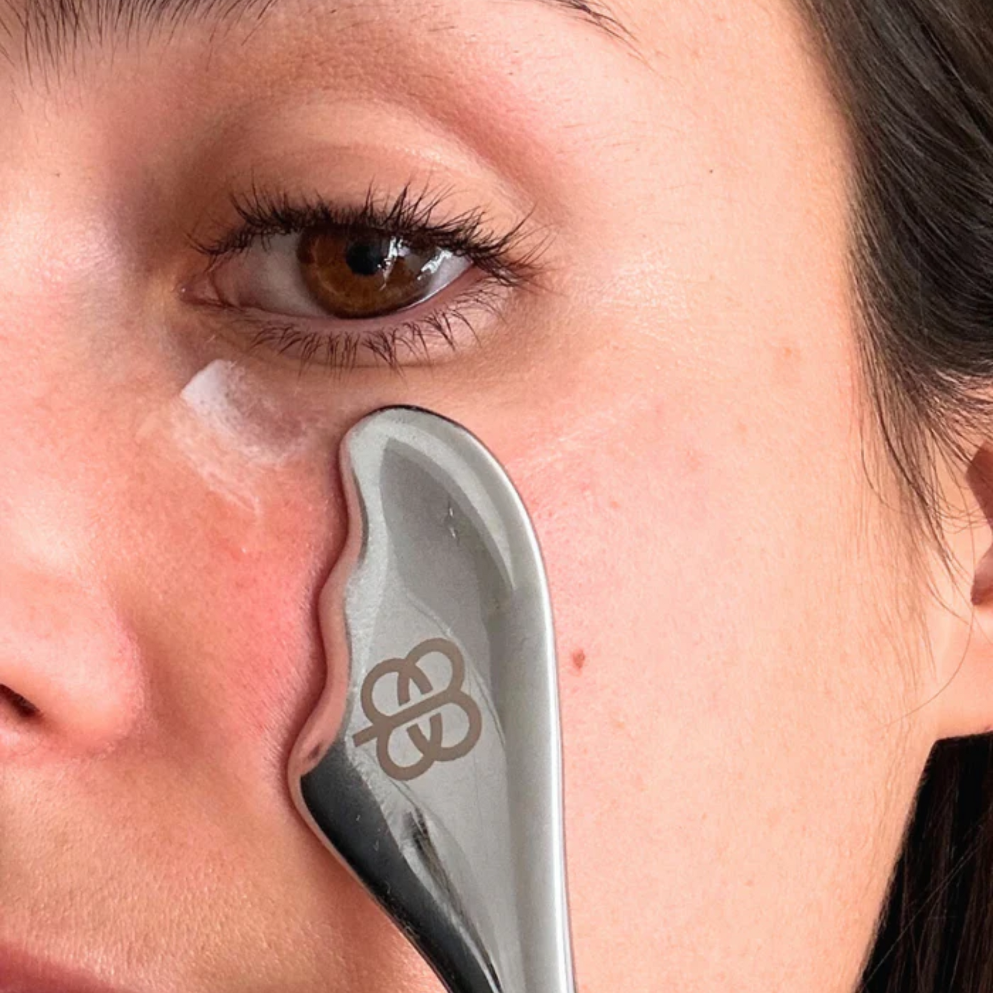 retrato de modelo usando el roller para masajes para aplicar el suero de ojos antiedad de edena