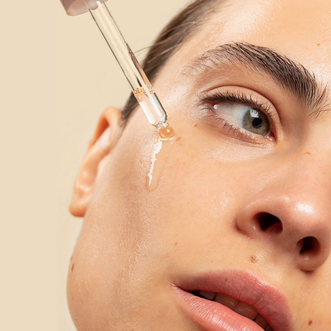 Mujer colocando el nectar facial de cipres Ere Perez en la mejilla disponible en BLUMMA