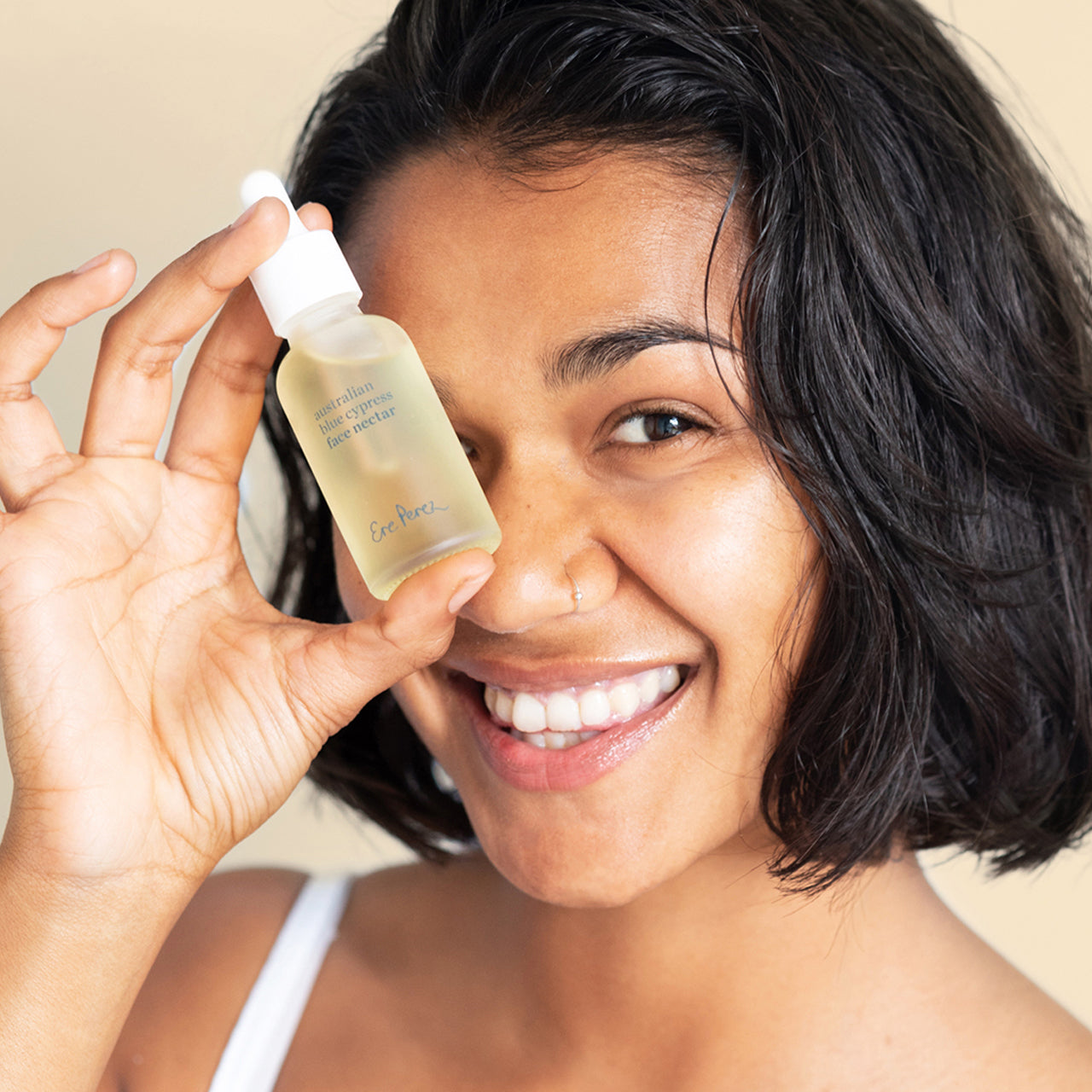Mujer sonriente mostrando el nectar facial de cipres Ere Perez disponible en BLUMMA