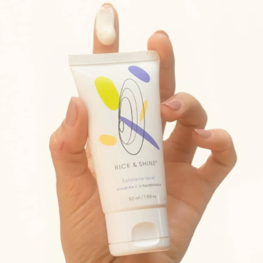 botella de plastico blanca con siendo sostenida en una mano mostrando la textura del exfoliante facial de vitamina-e rice and shine disponible en blumma