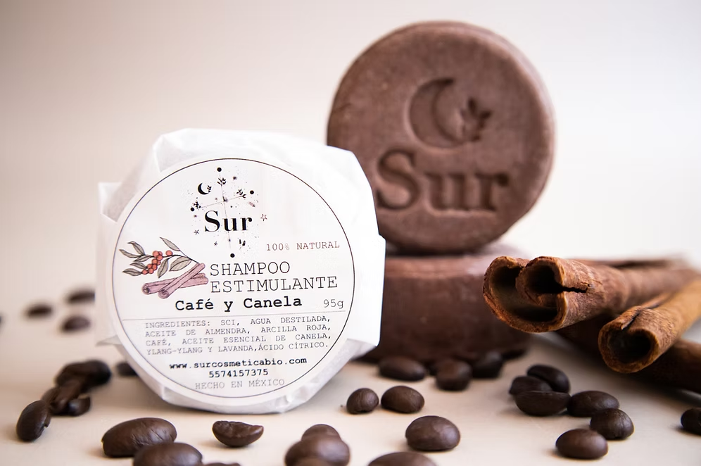 vista frontal del shampoo sólido estimulante café y canela de Sur Biocosmetica acompañado con granos disponible en Blumma